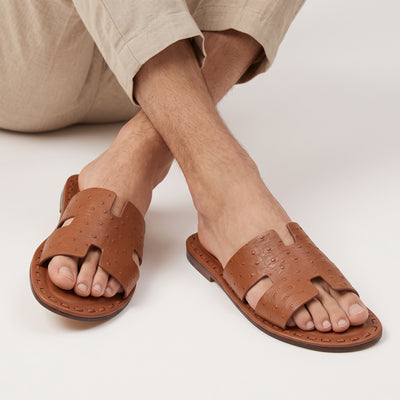 Hermès tan perforated leather men's slide sandals on model feet
