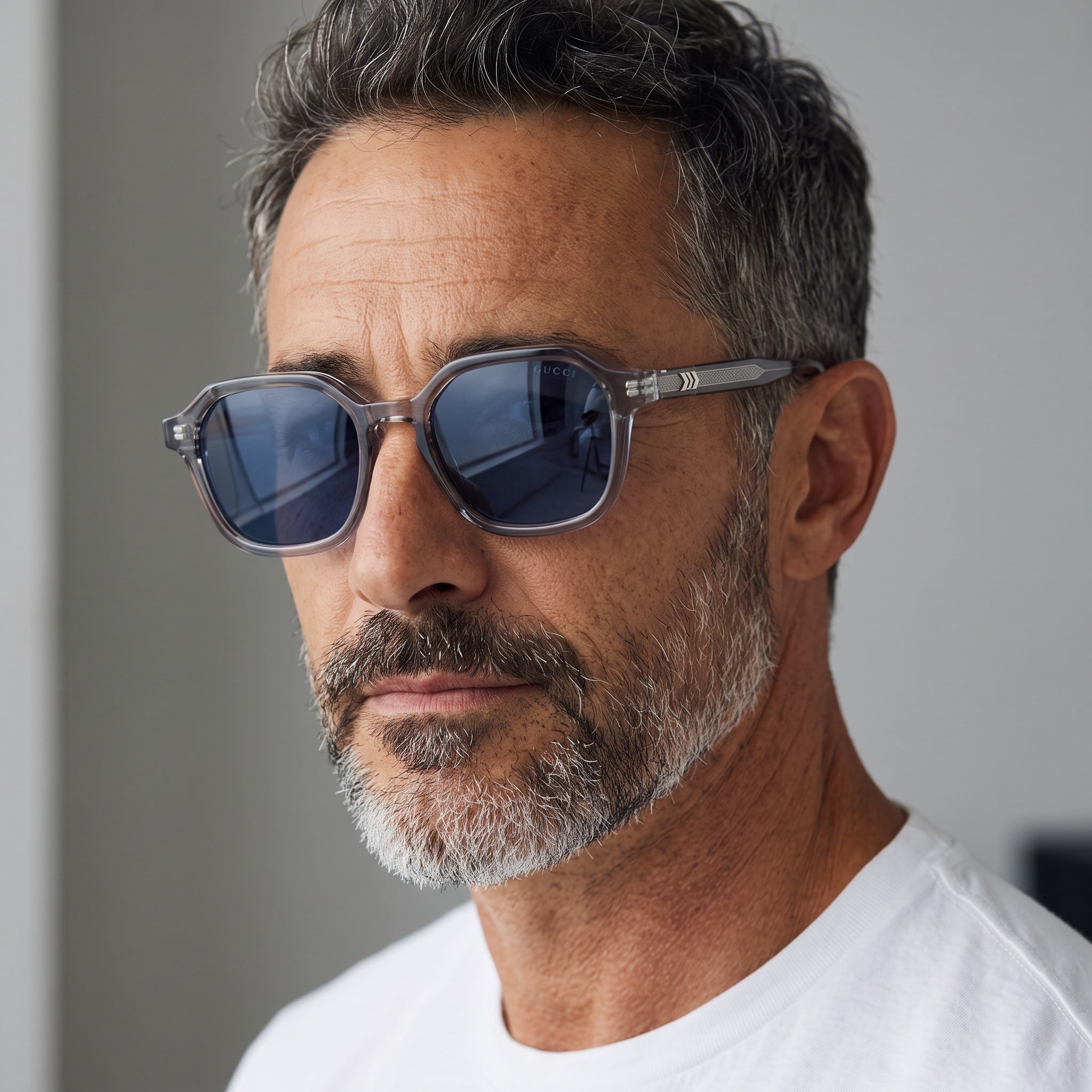 Close-up of a man wearing Gucci grey transparent sunglasses with blue-tinted lenses