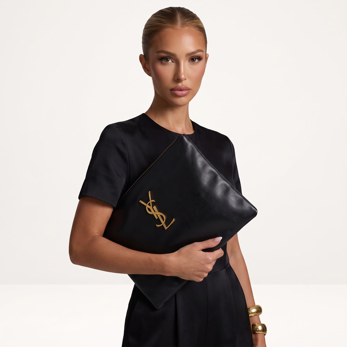 Saint Laurent black zip pouch with gold YSL logo held as a clutch
