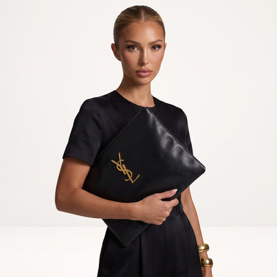 Saint Laurent black zip pouch with gold YSL logo held as a clutch