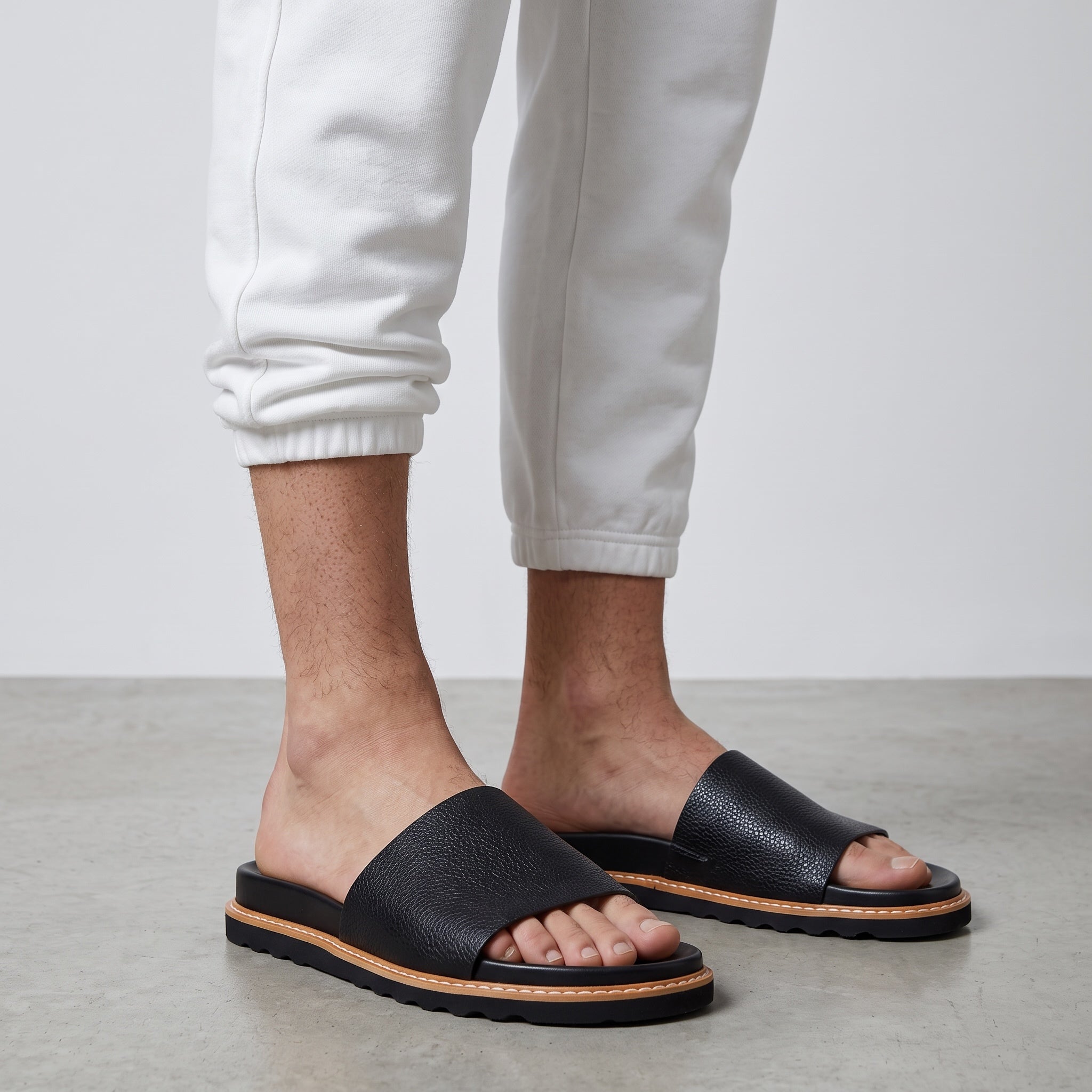 Brunello Cucinelli black pebbled single-strap sandals with stitched welt and printed footbed logo