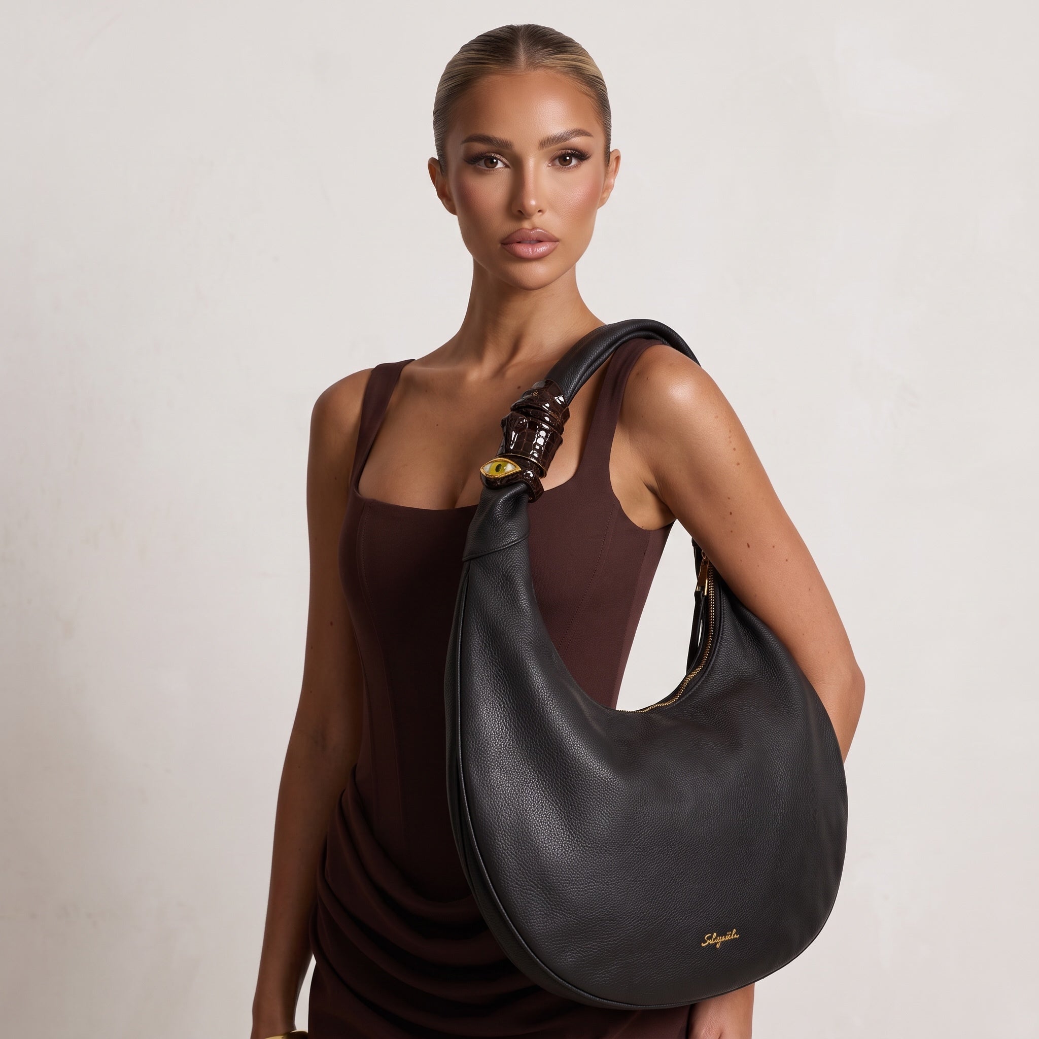 Black Schiaparelli crescent hobo shoulder bag with gold logo and eye charm on strap