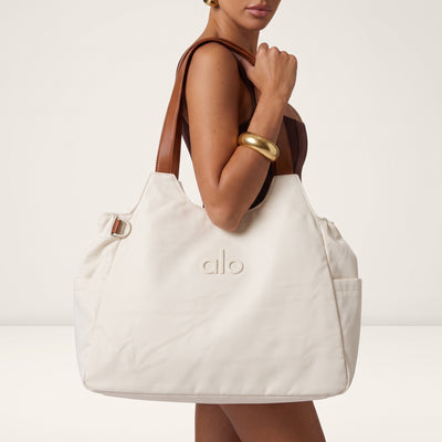 Cream Alo Yoga tote bag with tan double handles and embossed logo