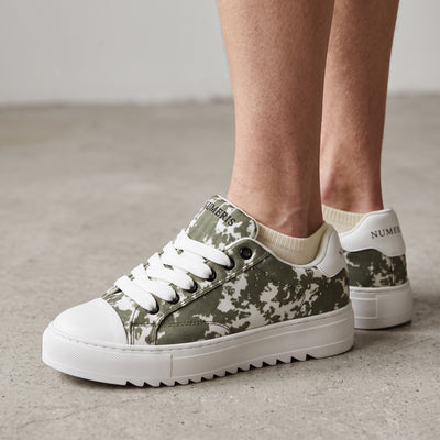 Numeris low-top green camo sneakers with white sole and serrated outsole