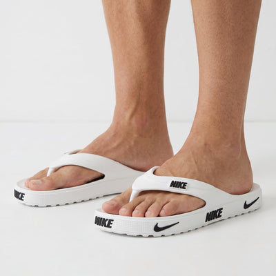 White Nike flip-flop sandals with black NIKE logos on strap and sole
