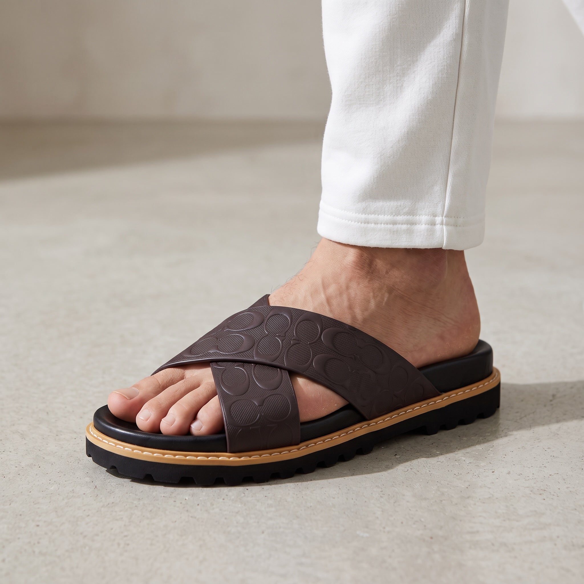 close-up of brown Coach crossover platform sandal with embossed logo straps