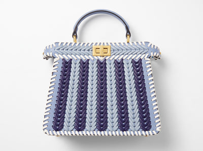 Light blue woven top-handle bag with white whipstitch trim and gold turn-lock clasp