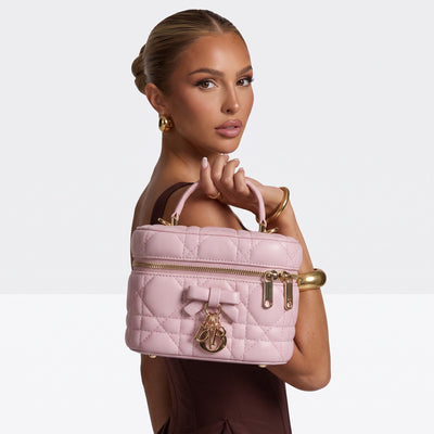 pink quilted Dior vanity bag with bow charm and top handle