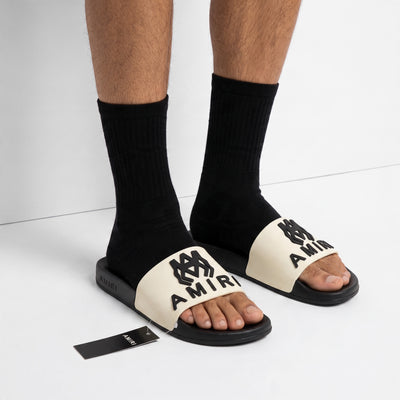 Amiri white strap black sole logo slides on model feet
