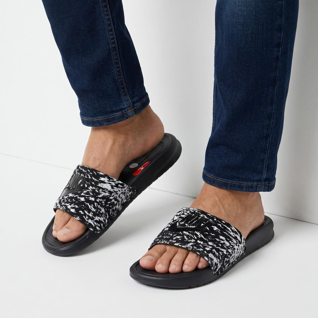 black and white speckled Nike slide sandals on model's feet