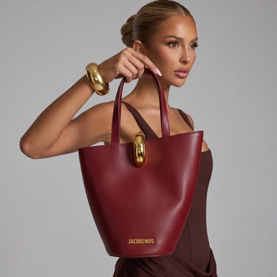 Burgundy Jacquemus tote with gold oval clasp and top handles