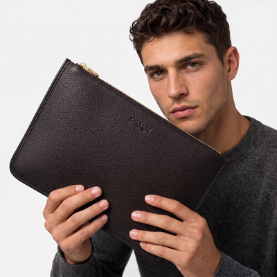 Black pebbled Coach zip pouch with gold zipper held by model