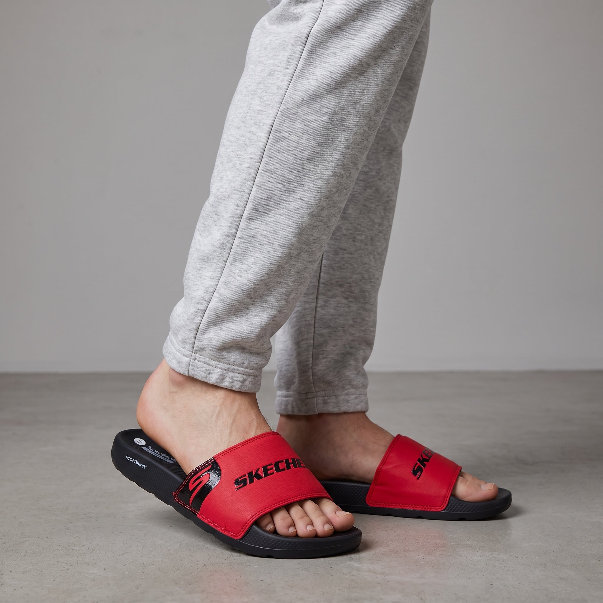 Red Skechers slide with black hyperburst recovery sole, worn on model feet