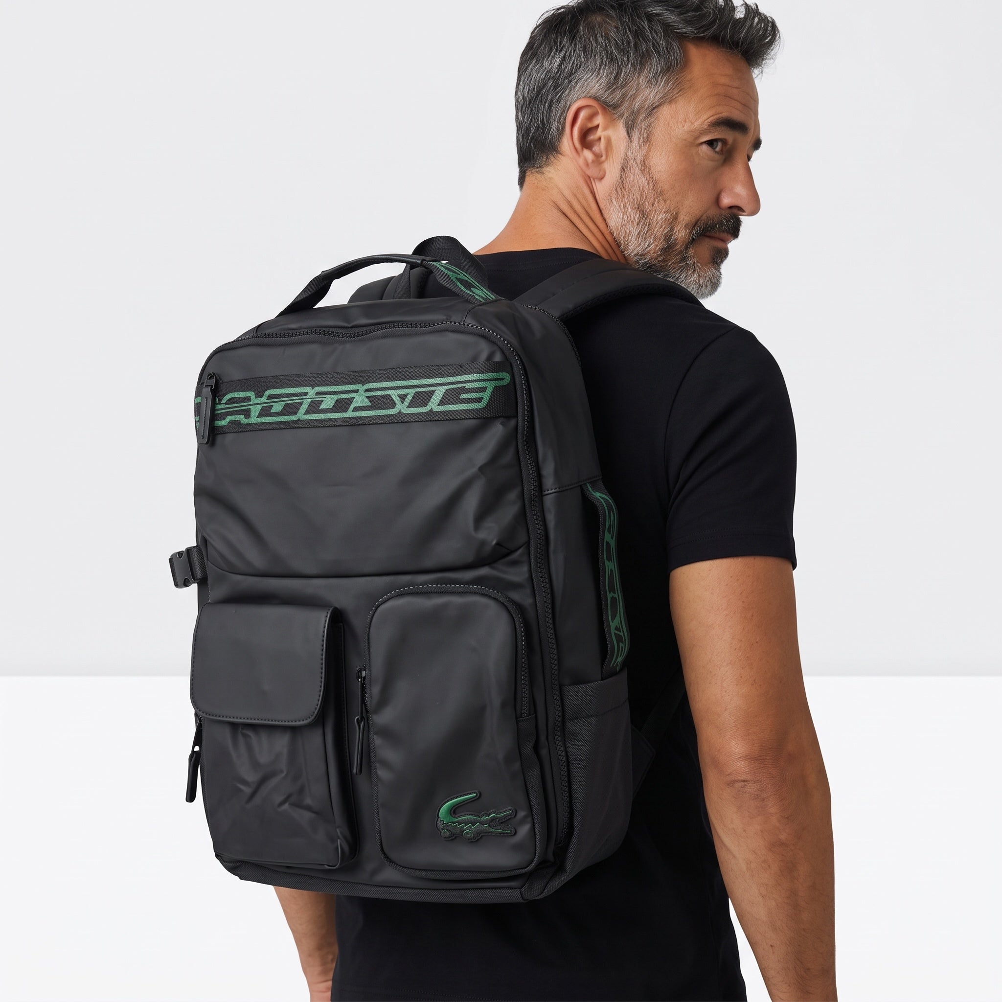 Black Lacoste backpack with green logo patches and multiple exterior pockets