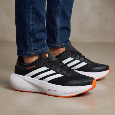 Adidas Supernova black white orange running sneaker showing Dreamstrike+ midsole and three stripes