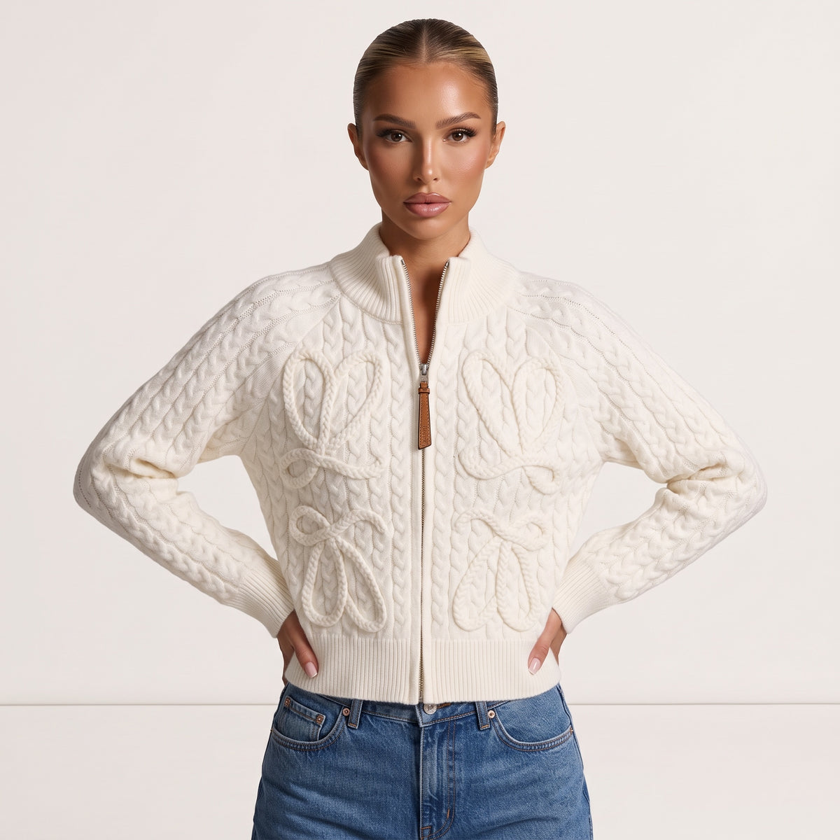 Ivory cable-knit zip jacket with rope bow details and leather zipper pull