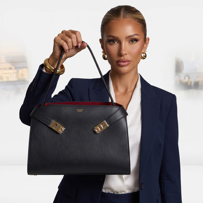 Ferragamo black structured top-handle bag with gold hardware held by model