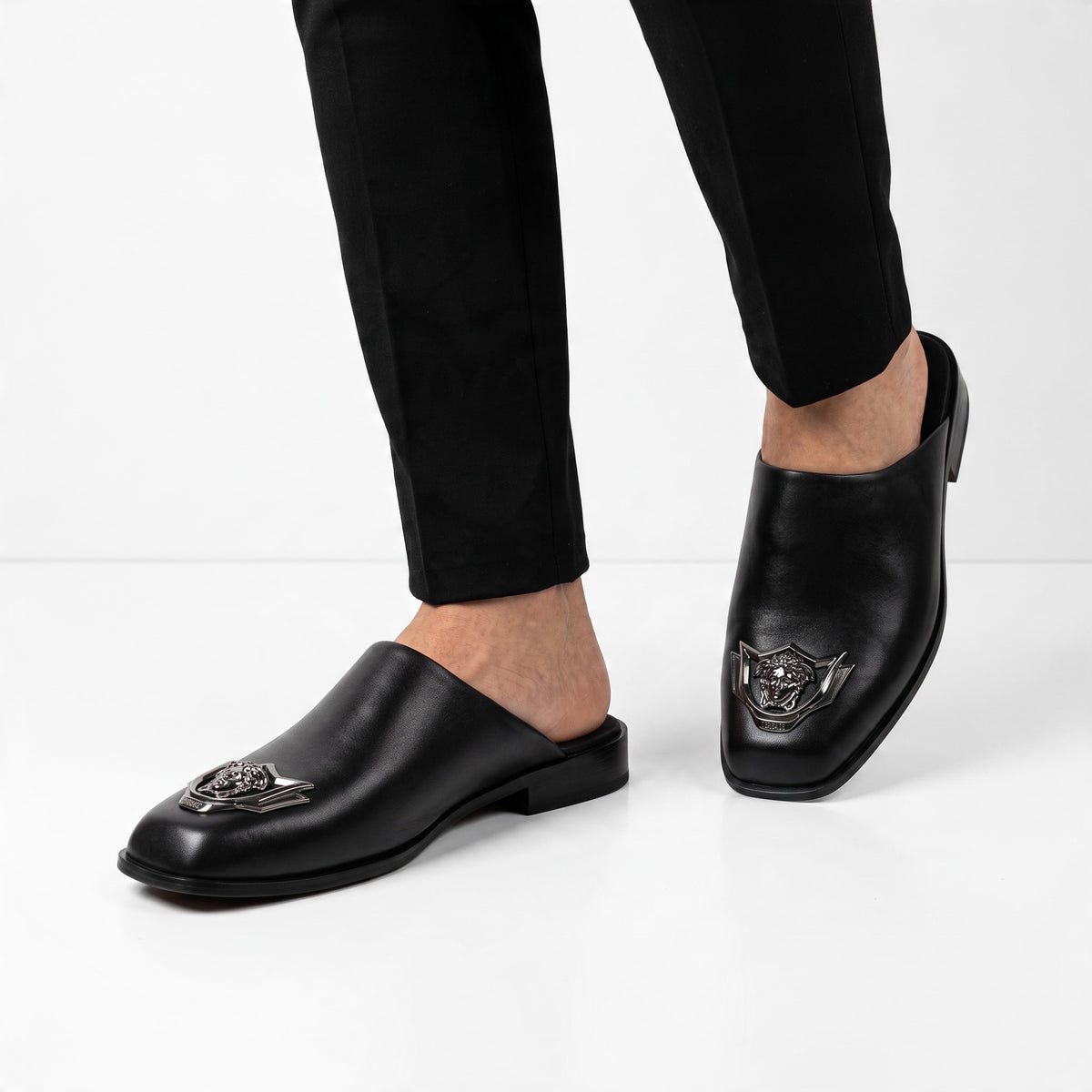 Black Versace mules with metal Medusa badge shown on model feet