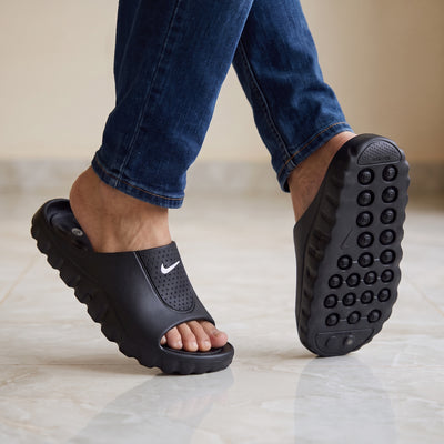 black Nike slip-on slide with white swoosh and sculpted sole