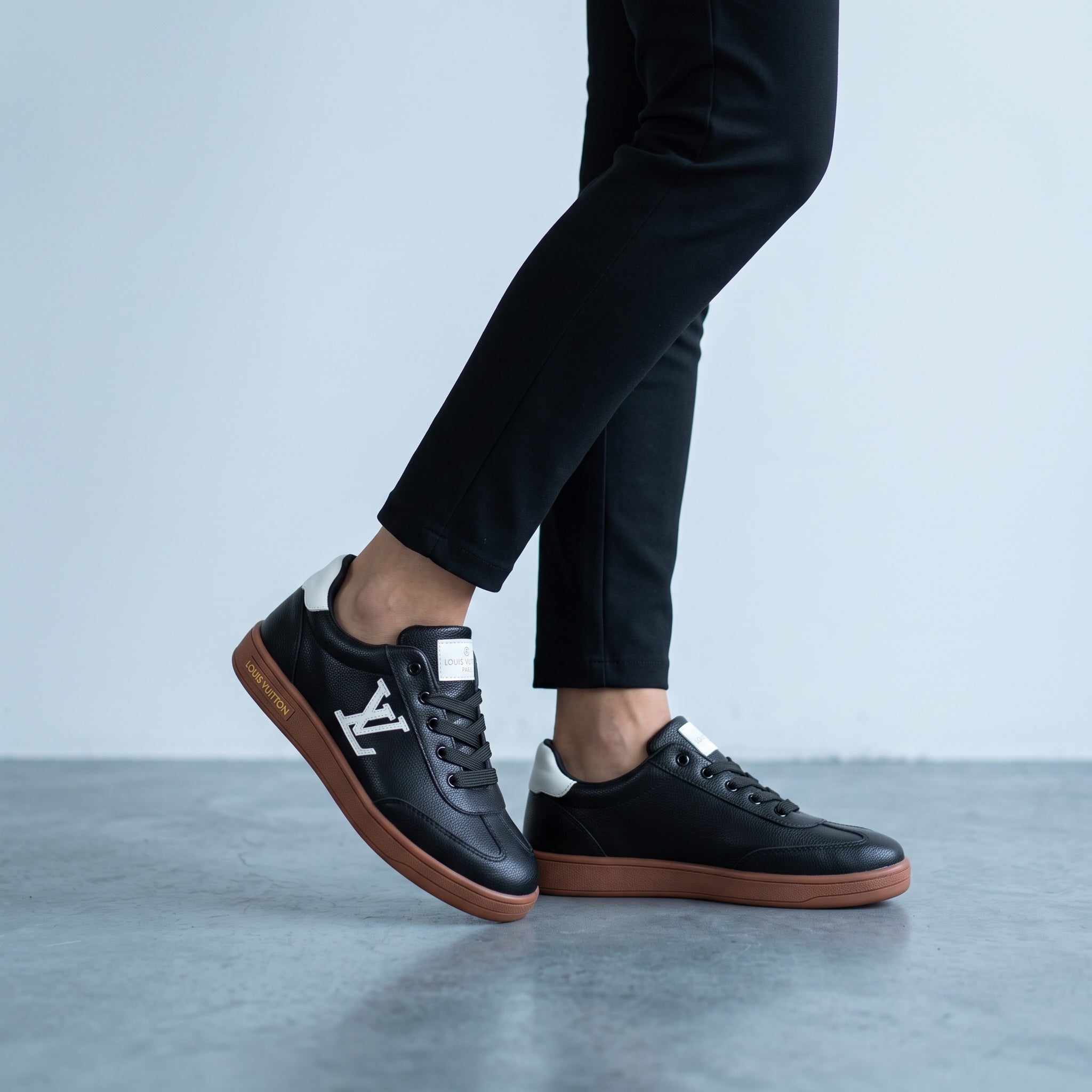 Black Louis Vuitton low-top sneakers with brown gum sole and visible LV logo on side