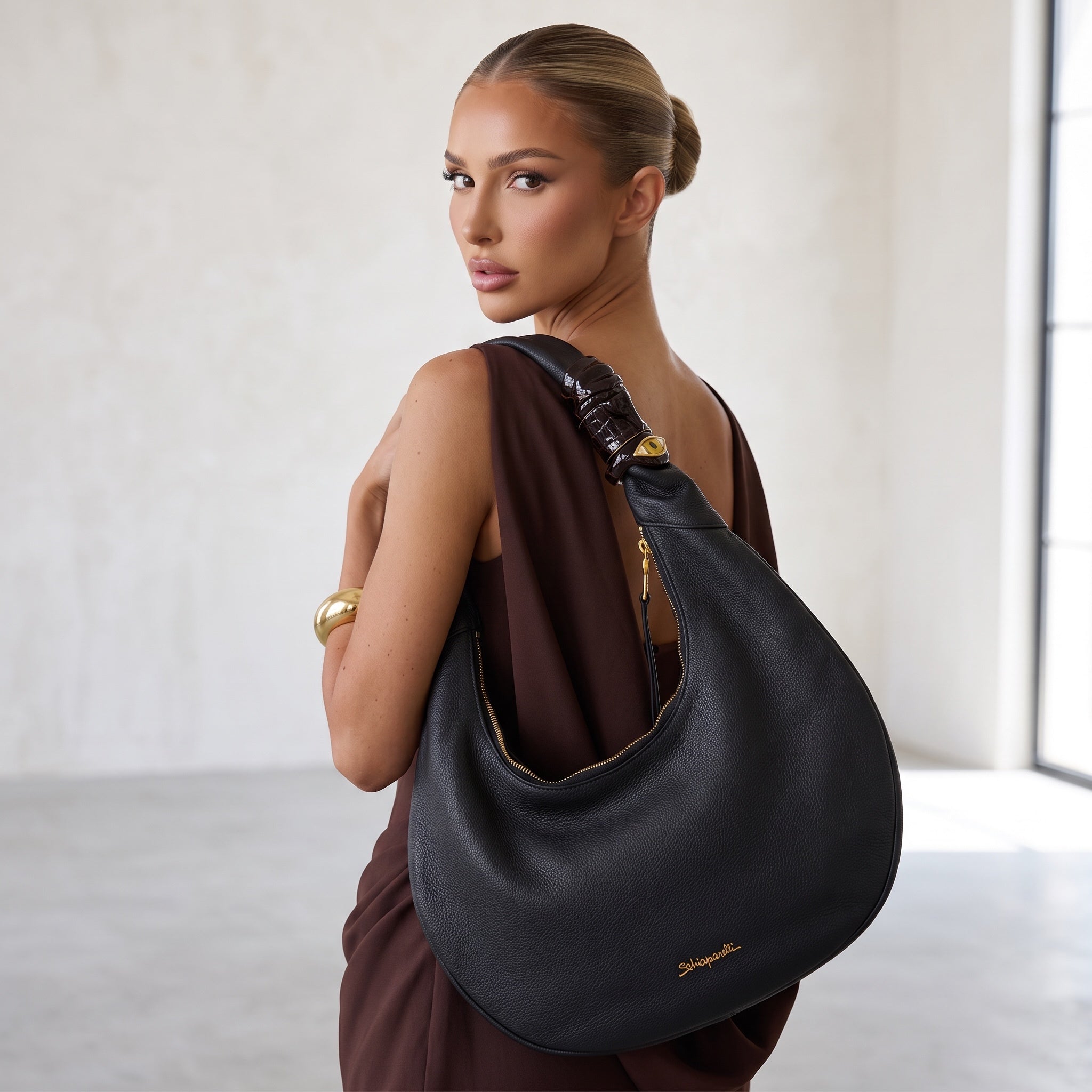 Black Schiaparelli crescent hobo shoulder bag with gold logo and eye charm on strap
