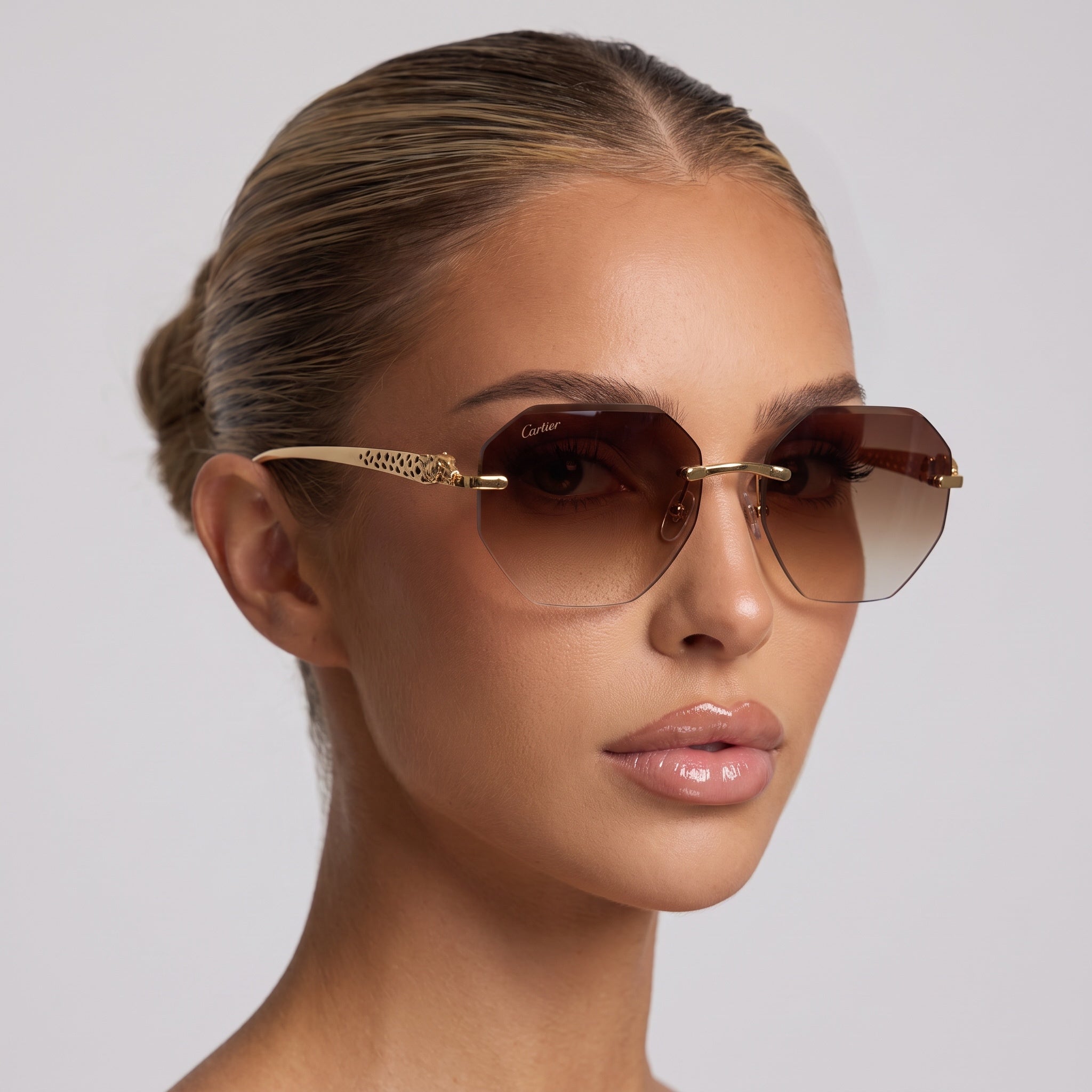 Close-up of Cartier rimless sunglasses with brown gradient lenses and gold-tone temples