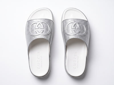 Silver Gucci flatform slides with glitter finish and raised interlocking G logo on white footbed