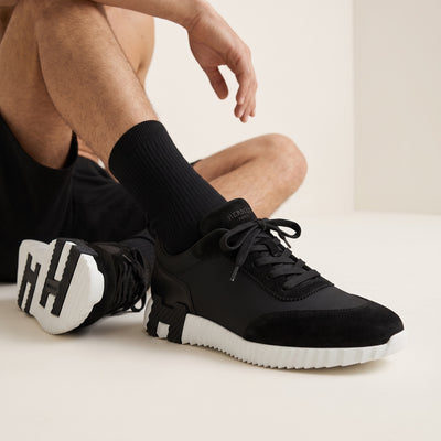 Hermès black low-top sneaker with white ridged sole and H-shaped black insert