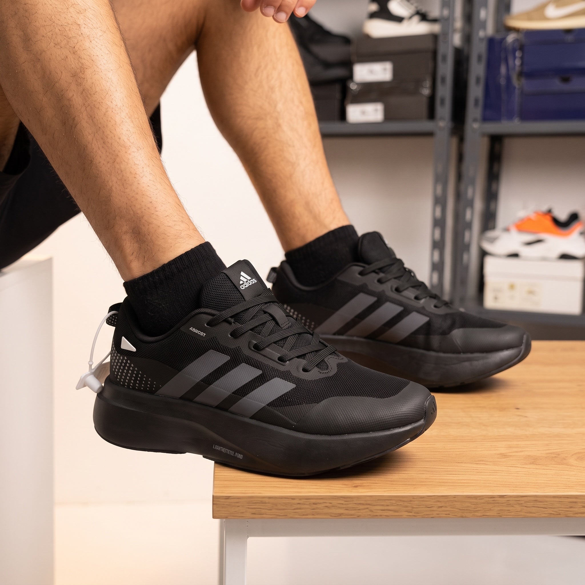 adidas adizero all-black running sneakers shown on model feet