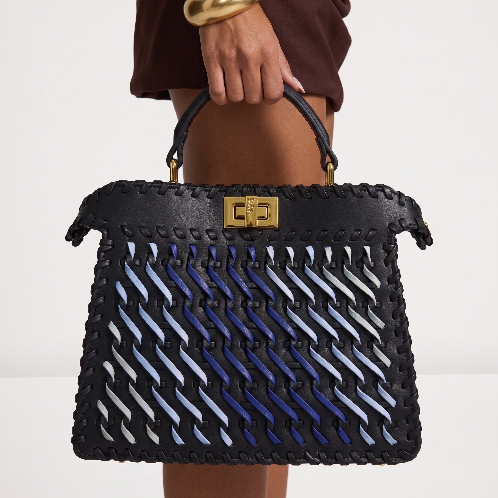 black top-handle bag with blue woven ribbon accents and gold rectangular clasp