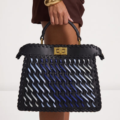 black top-handle bag with blue woven ribbon accents and gold rectangular clasp