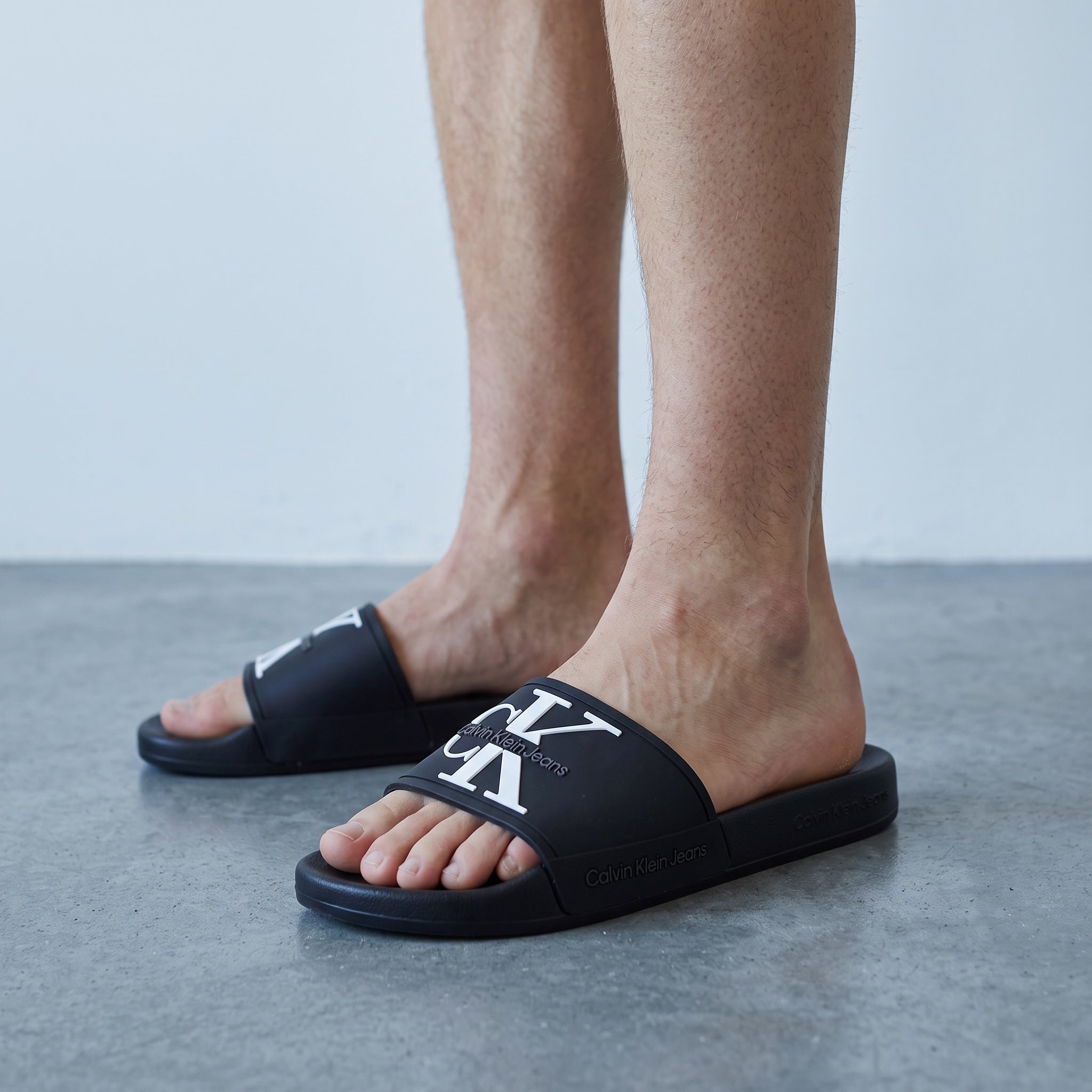 black Calvin Klein logo slide sandals on model feet