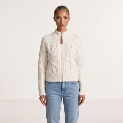 Ivory cable-knit zip jacket with rope bow details and leather zipper pull