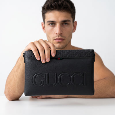 Black Gucci embossed logo pouch with GG motif and green-red tab