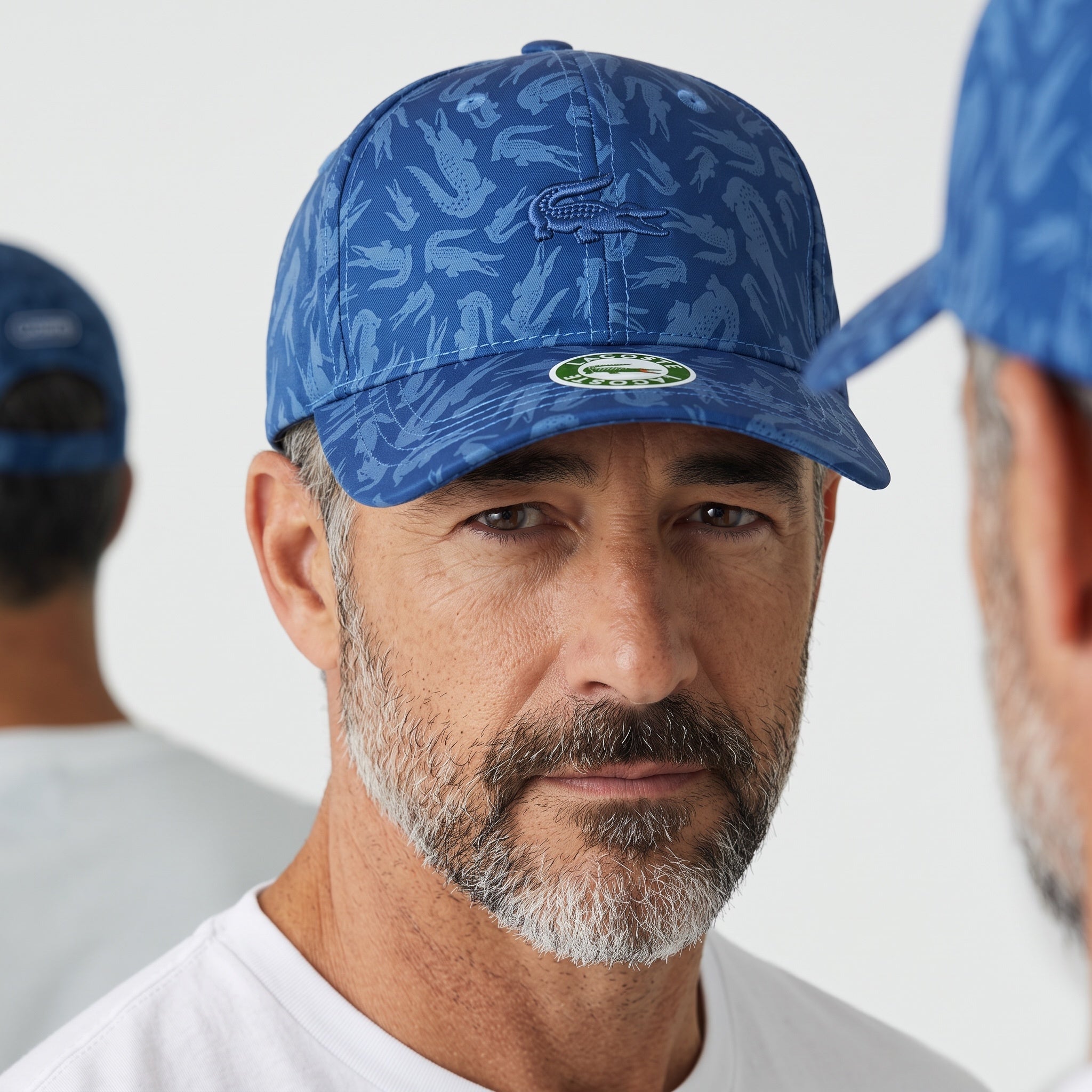 Man wearing a blue Lacoste baseball cap with allover crocodile print and embroidered logo