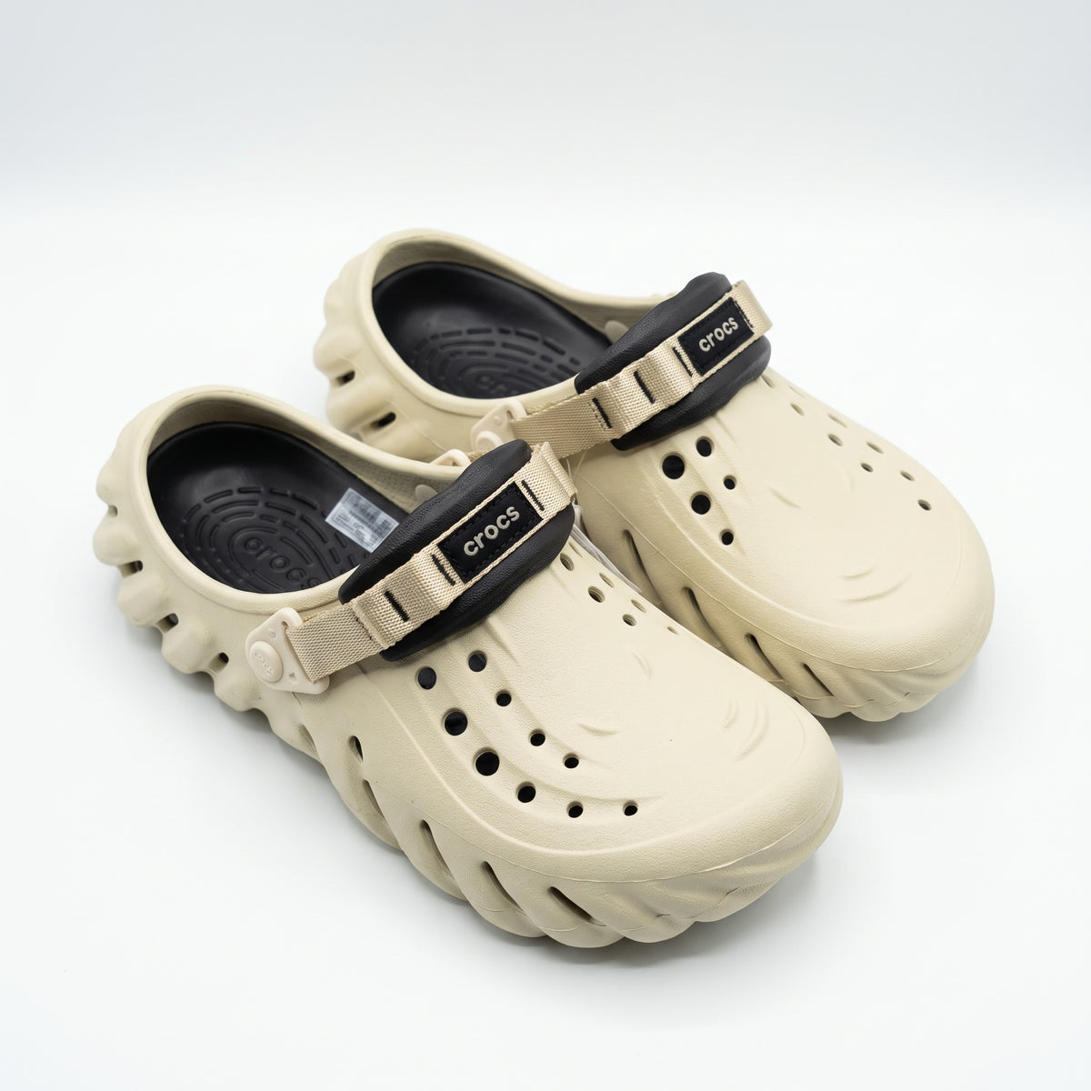 Pair of sand beige Crocs clogs with black footbed and beige strap