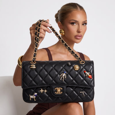 Black quilted Chanel flap bag with gold chain strap and decorative pins