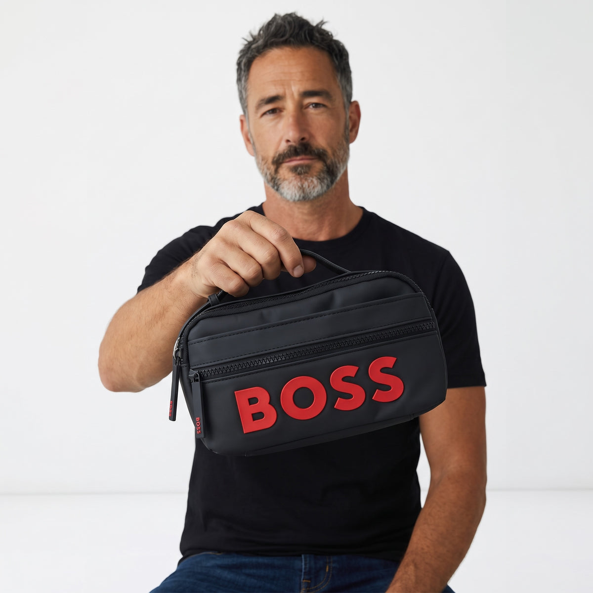 Black BOSS travel pouch with raised red logo held by man