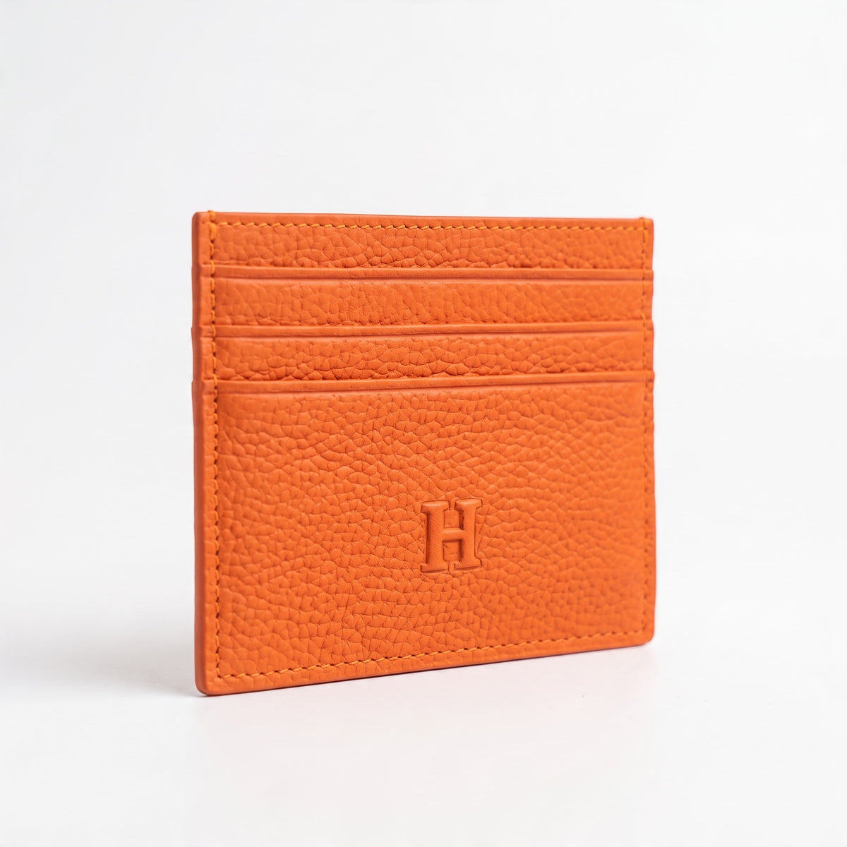 Orange Hermès pebbled leather card holder with embossed H and Hermès Paris stamp