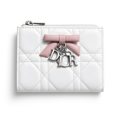 White quilted Dior compact wallet with pink bow and silver Dior charms, opened to show pink interior card slots
