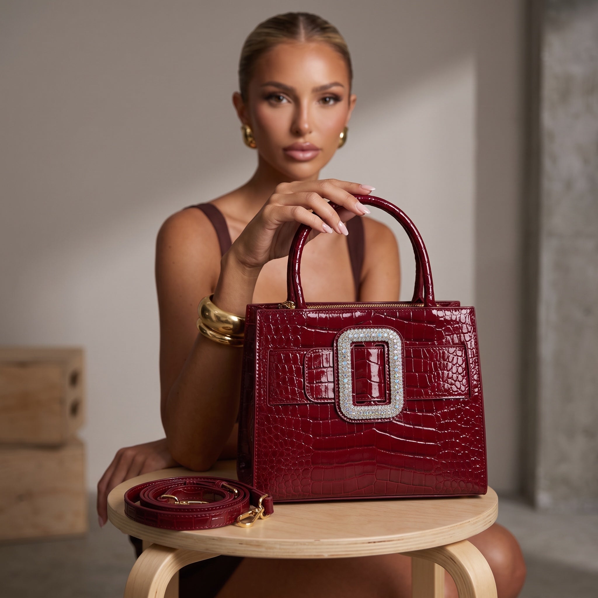 Glossy burgundy croc-effect top-handle tote with large crystal buckle and gold hardware