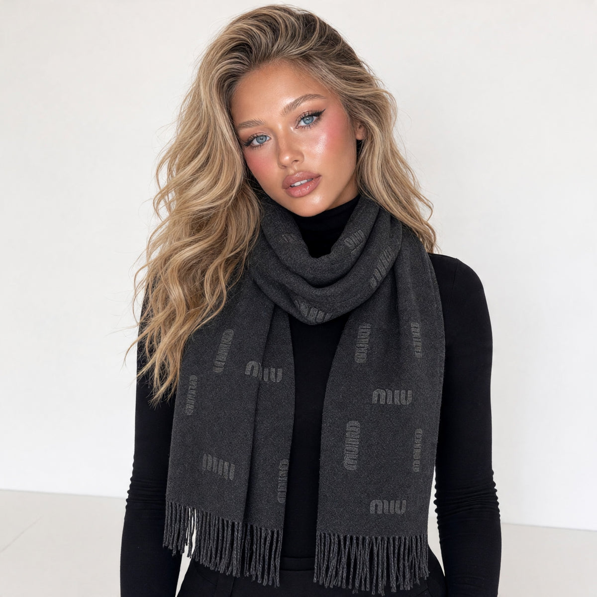 Charcoal Miu Miu knit scarf with repeating MIU logo and fringe wrapped on model