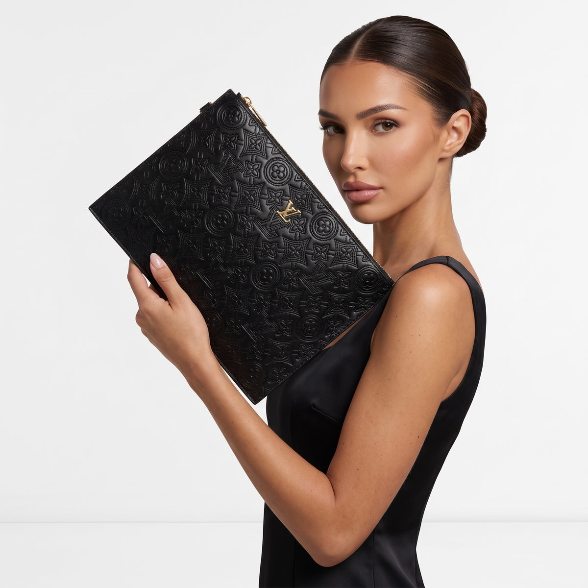 Louis Vuitton black embossed monogram flat pouch with gold zipper held by model