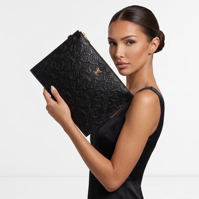 Louis Vuitton black embossed monogram flat pouch with gold zipper held by model