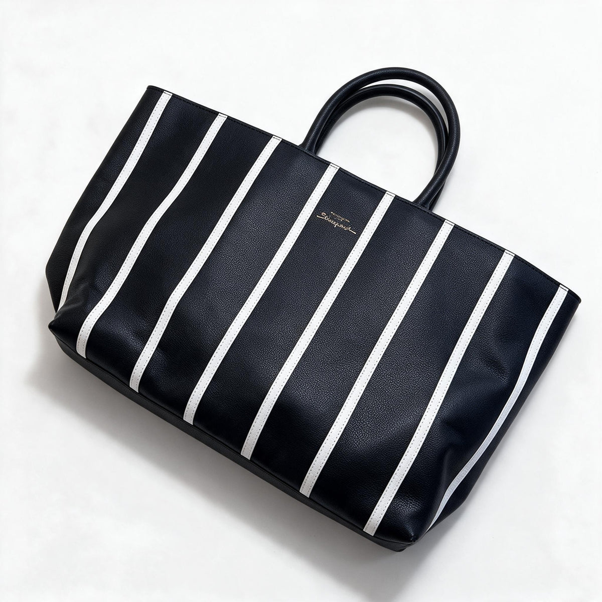 Black tote bag with vertical white stripes and gold keyhole plaque