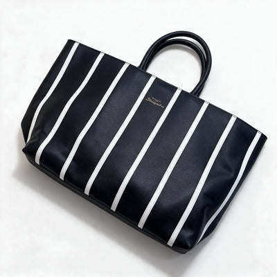Black tote bag with vertical white stripes and gold keyhole plaque