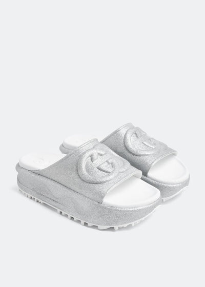 Silver Gucci flatform slides with glitter finish and raised interlocking G logo on white footbed