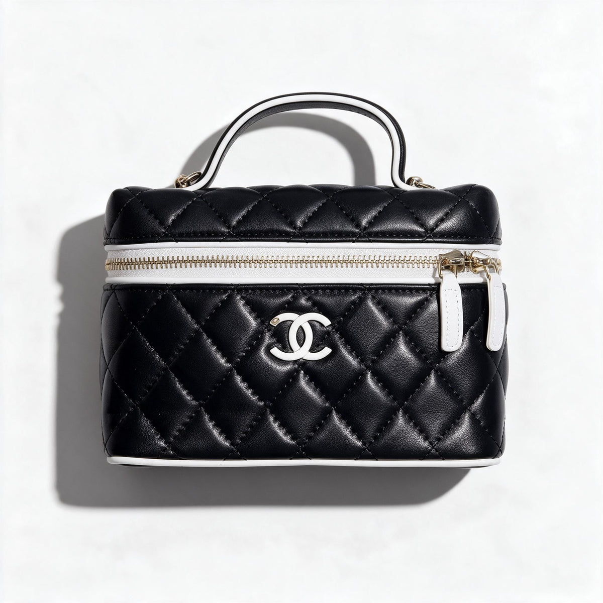 black quilted Chanel vanity case with white trim and CC logo