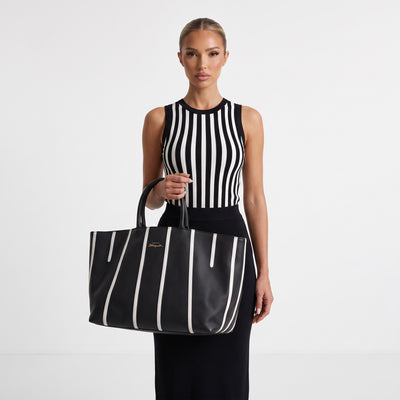 Black tote bag with vertical white stripes and gold keyhole plaque