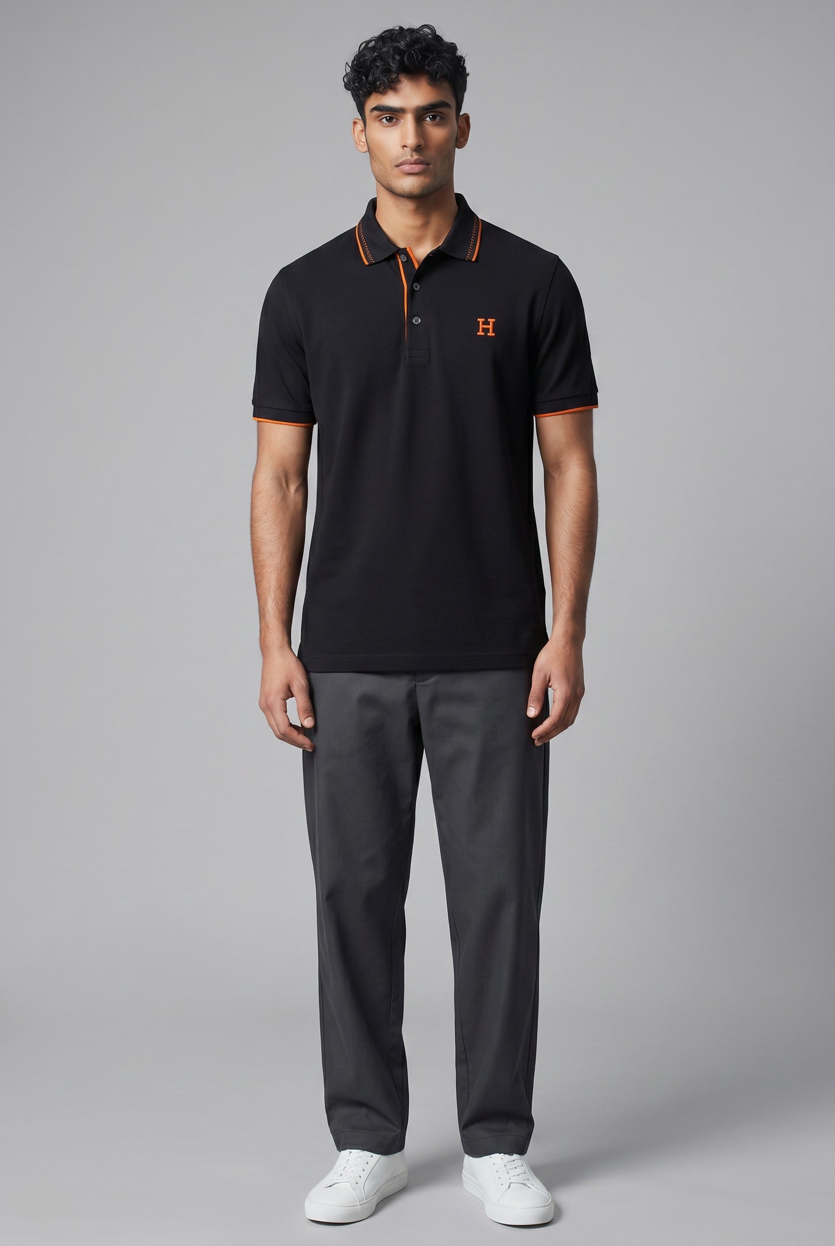 MASTERPIECE black textured polo shirt with orange embroidered H logo and trim. Classic collar, button placket, tailored fit.
